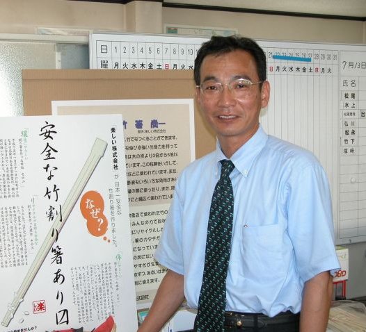安全な竹製割り箸の利用を呼びかけるポスターの前で熱心に説明する松尾社長。
